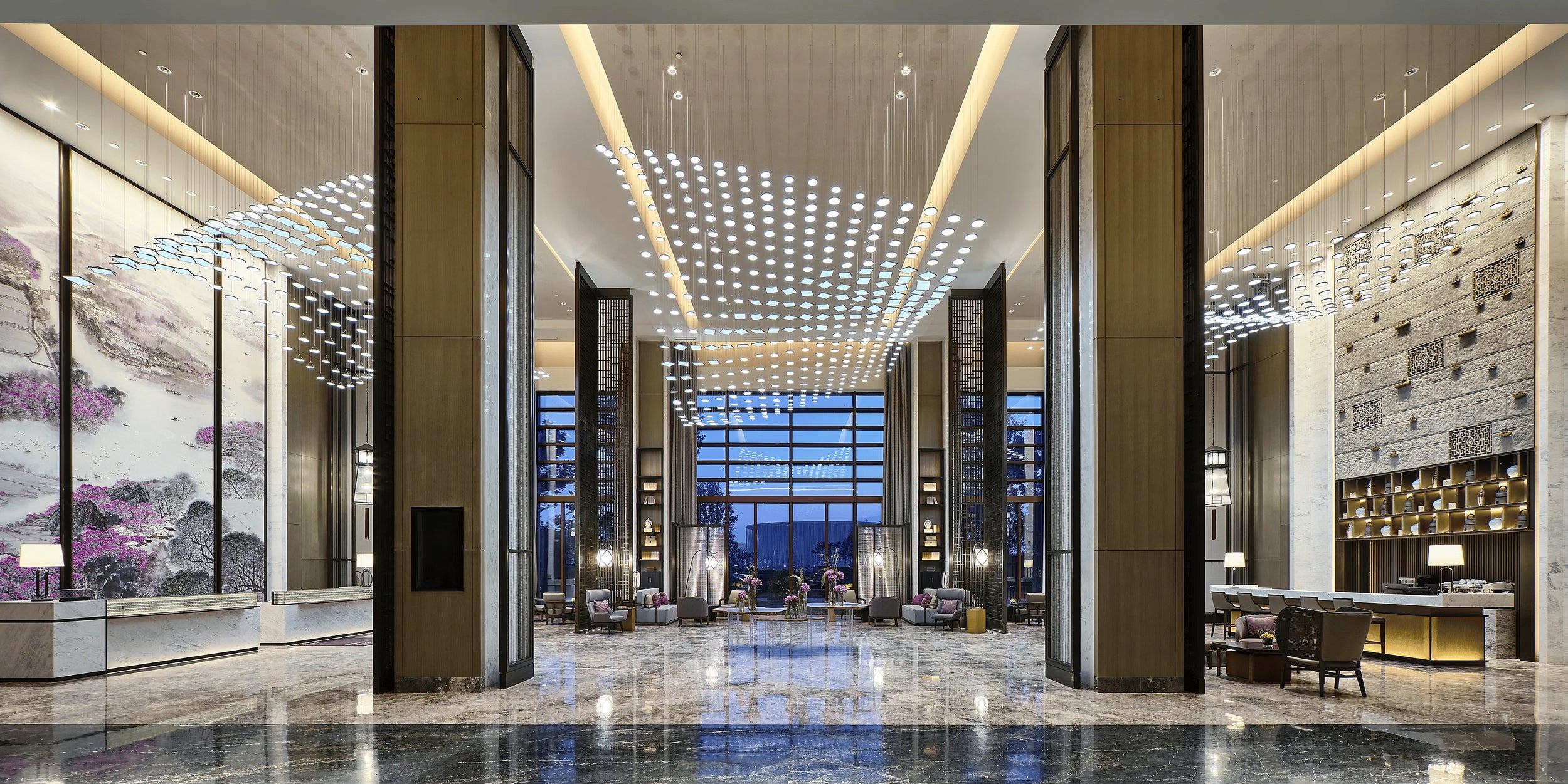 Hotel lobby with fret-cut stainless screen columns, a painted landscape mural and a marble floor