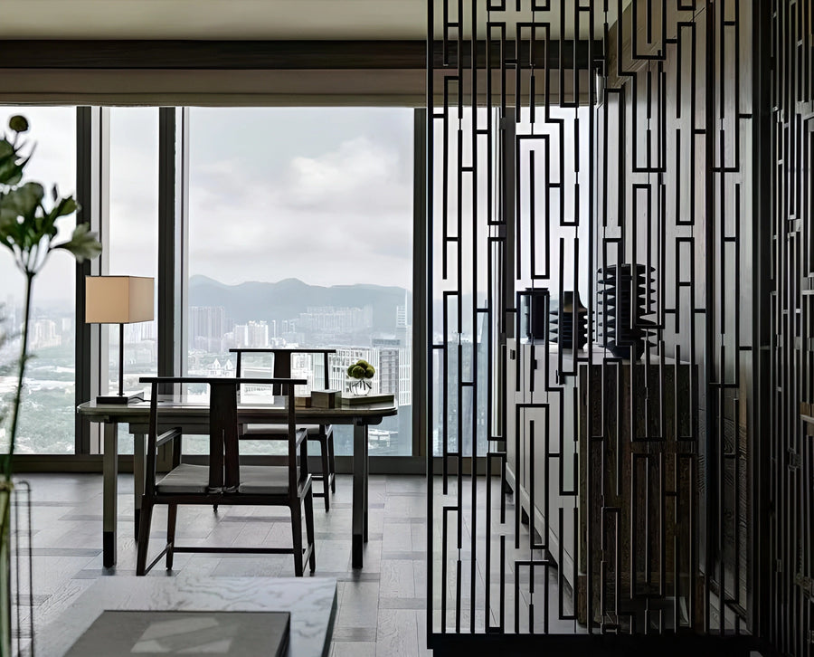 Blackened steel fret-pattern screen dividing an executive office lounge with a city skyline beyond