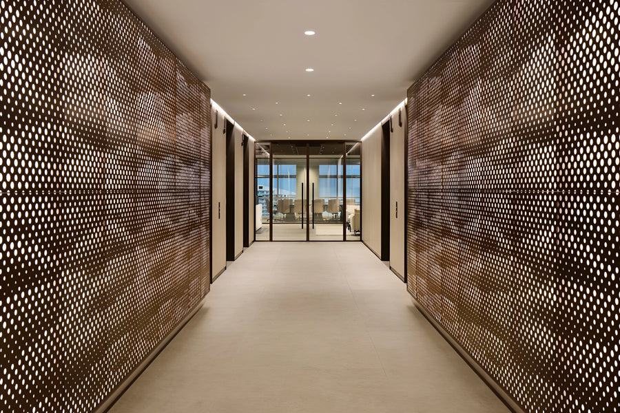 Bronze perforated metal screen walls lining a corridor in a Shenzhen tech office, leading to a glass-walled meeting room