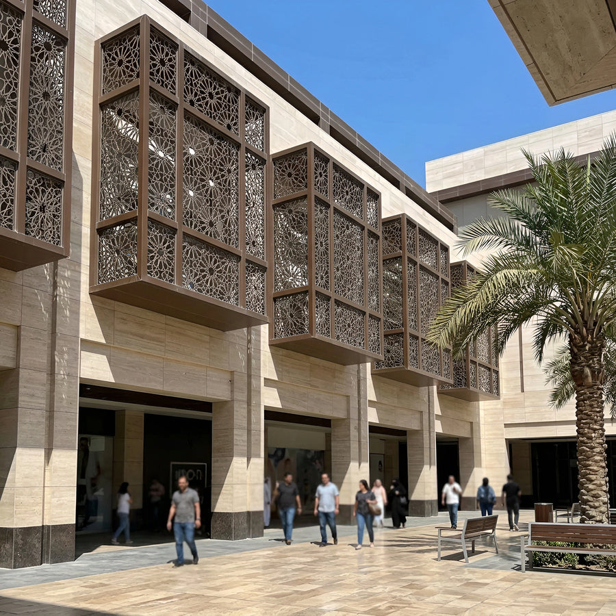 Bronze-toned geometric laser-cut shading screens on a limestone mall facade, Dubai Hills — visualization